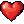 Pulsating ruby-red pixelated heart against a dark checkered background.