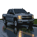 Dark grey Chevrolet Silverado 1500 driving on a wet track at night, headlights illuminated.