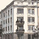 A pixel art building stands tall, showcasing its classical architecture with ornate windows and balconies. The muted color palette evokes a sense of timeless elegance and urban sophistication. Details in the building's construction are set on display for the viewer.