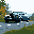 A dark car speeds through a pixelated landscape under an overcast sky. This simple yet evocative image captures a sense of movement and quiet melancholy in its muted tones.