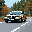 A black car speeds along a winding road in this pixel art scene, its headlights cutting through an autumn landscape. The retro aesthetic evokes a sense of a nostalgic road trip.