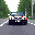 A black car speeds down a road, its rear lights glowing in this pixel art depiction of movement. The low-angle perspective and muted colors create a nostalgic, simplified driving scene.