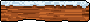 This pixel art depicts a textured brown block, possibly bricks or weathered stone, topped with a layer of white and light blue, resembling snow, ice, or frosting. The stark contrast against the black background emphasizes the object's simple yet evocative form.